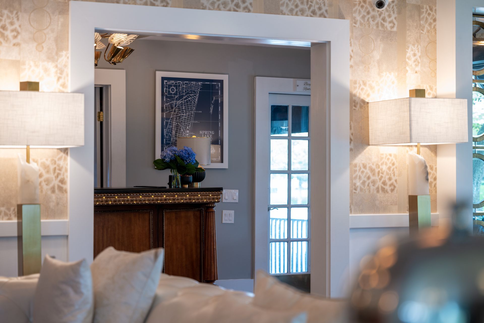 A living room with a couch , lamps , and a doorway leading to a hallway.