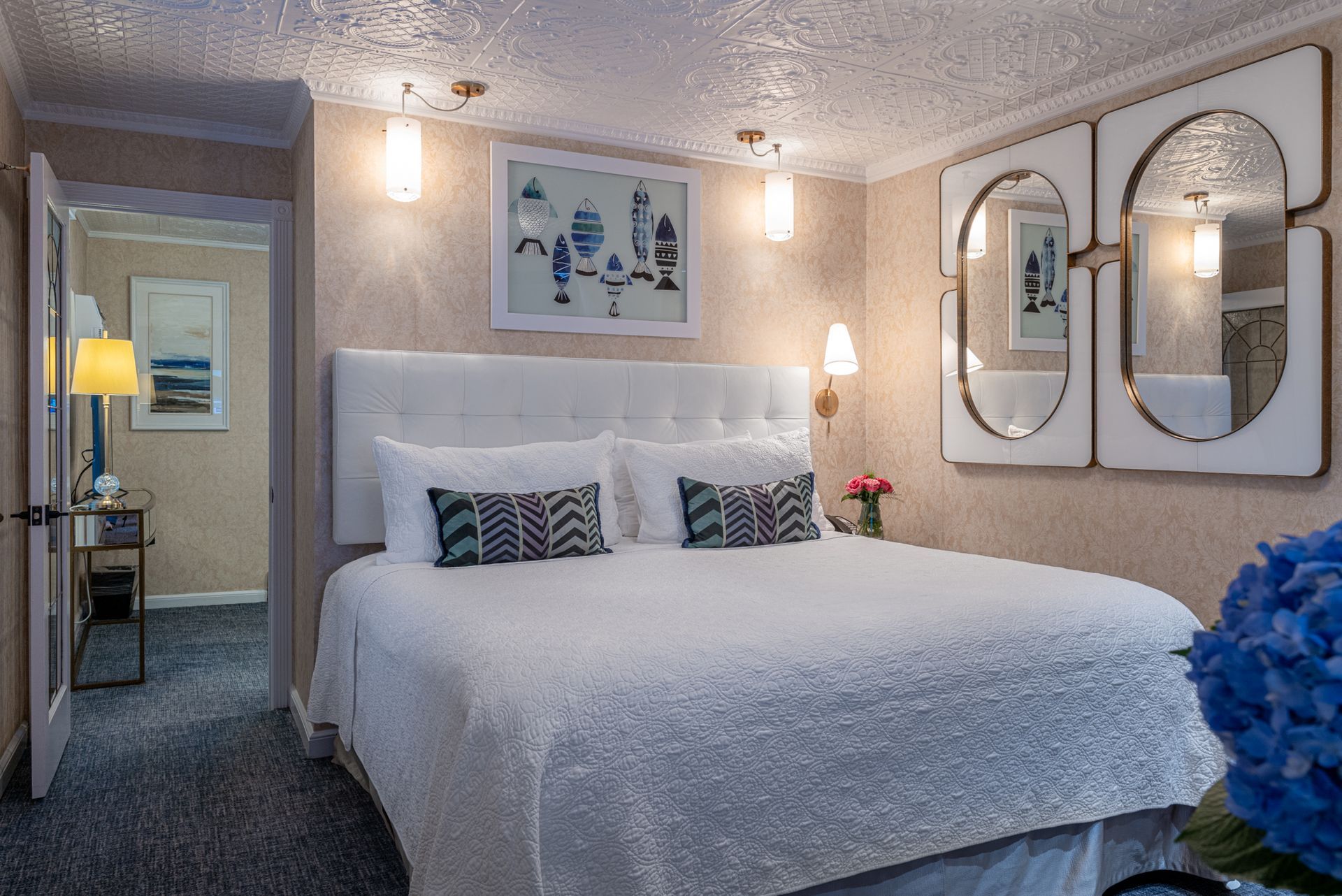 A hotel room with a king size bed and mirrors on the wall.