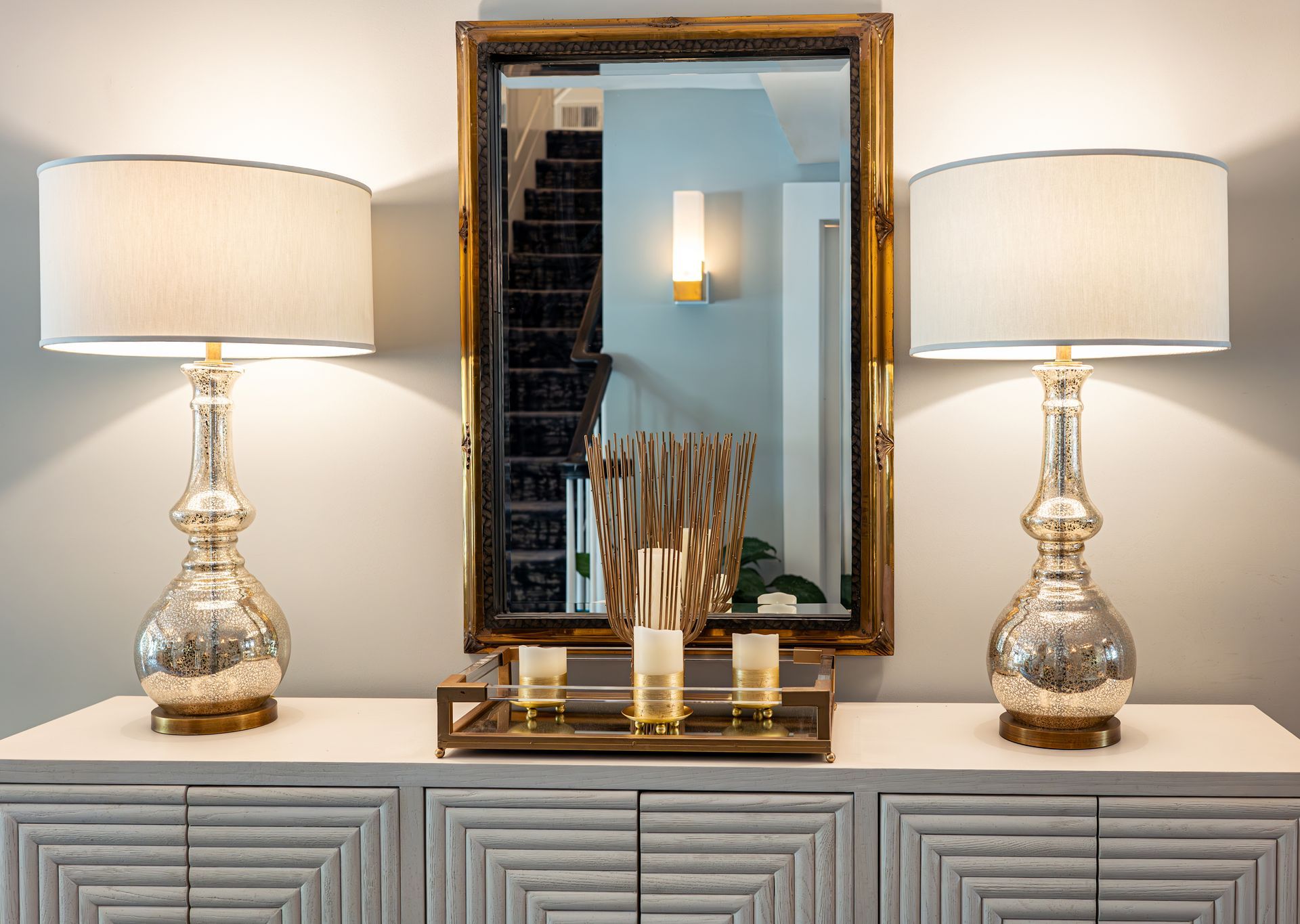 Two lamps are sitting on a dresser next to a mirror.