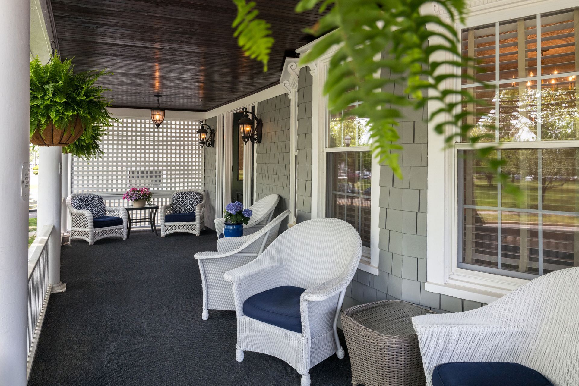 A porch with white wicker chairs and a table.