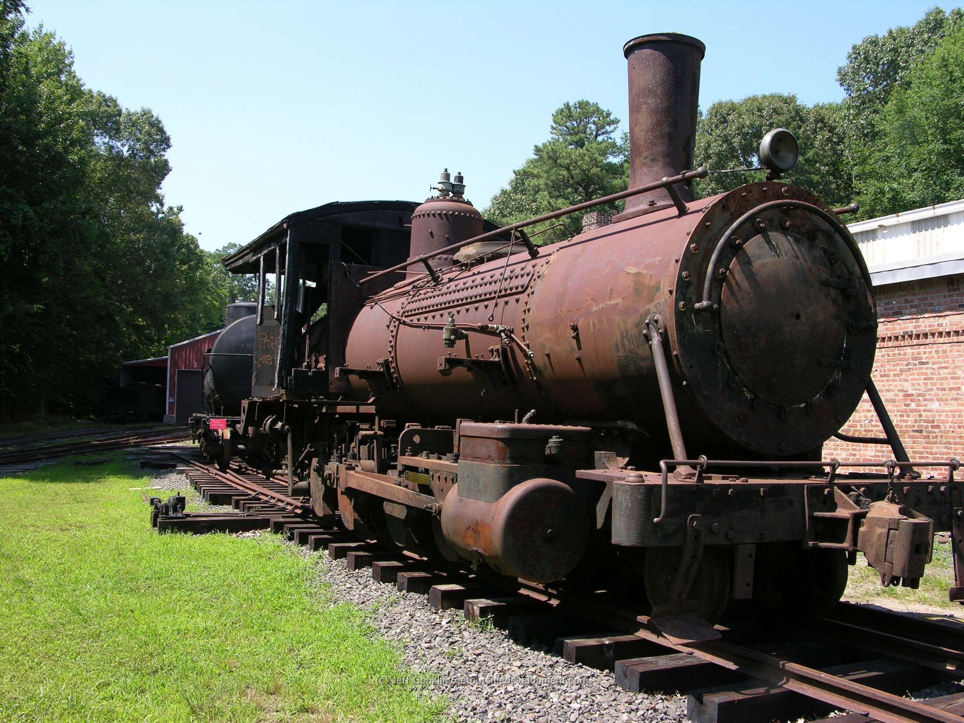 An old rusty train is on the tracks in a field