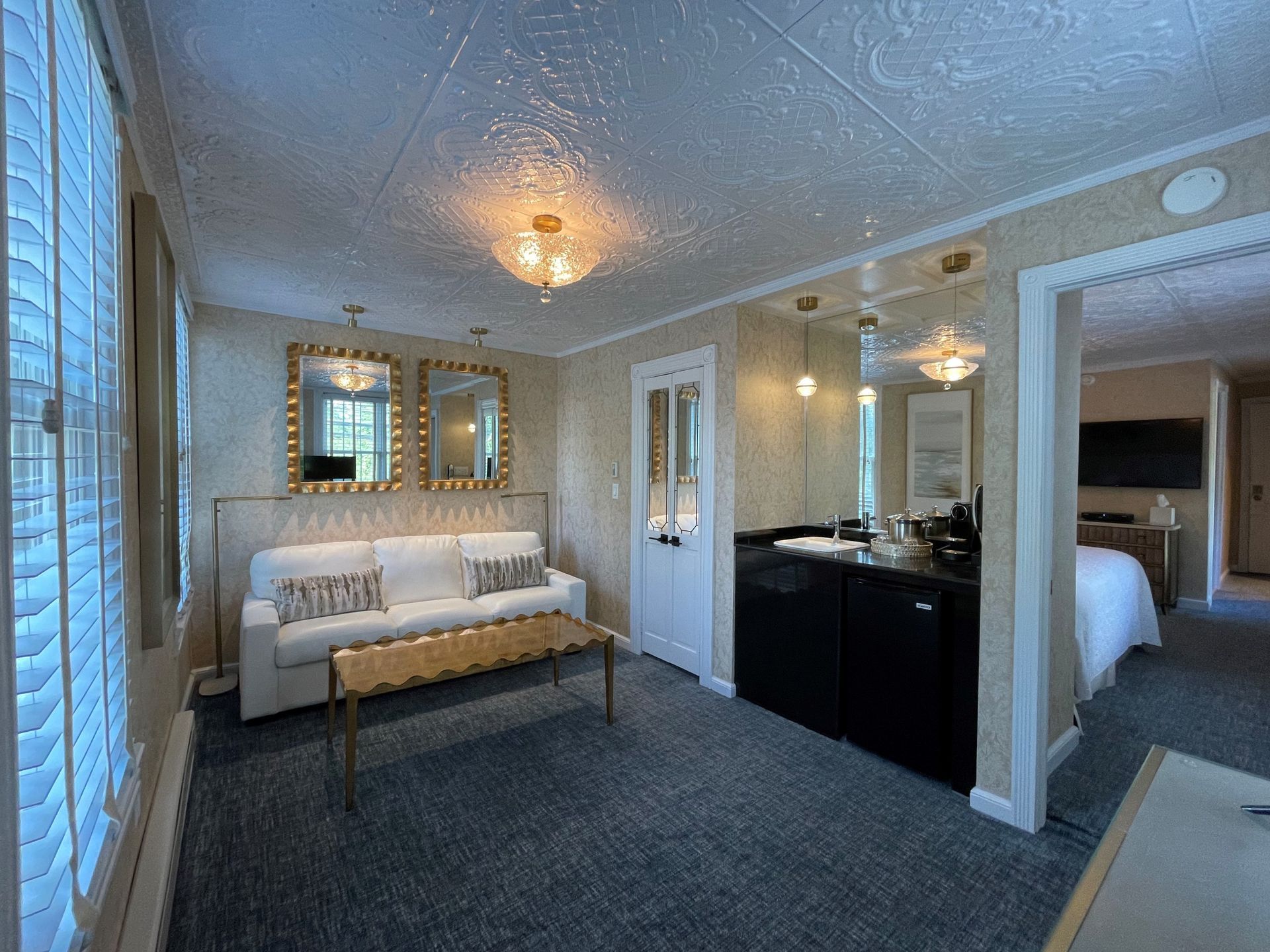 A hotel room with a couch , coffee table , and mirrors.