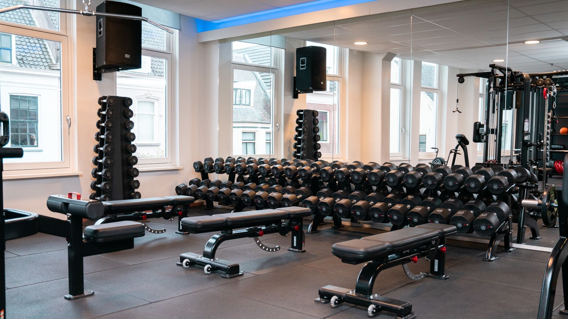 Een sportschool vol met halters en banken.