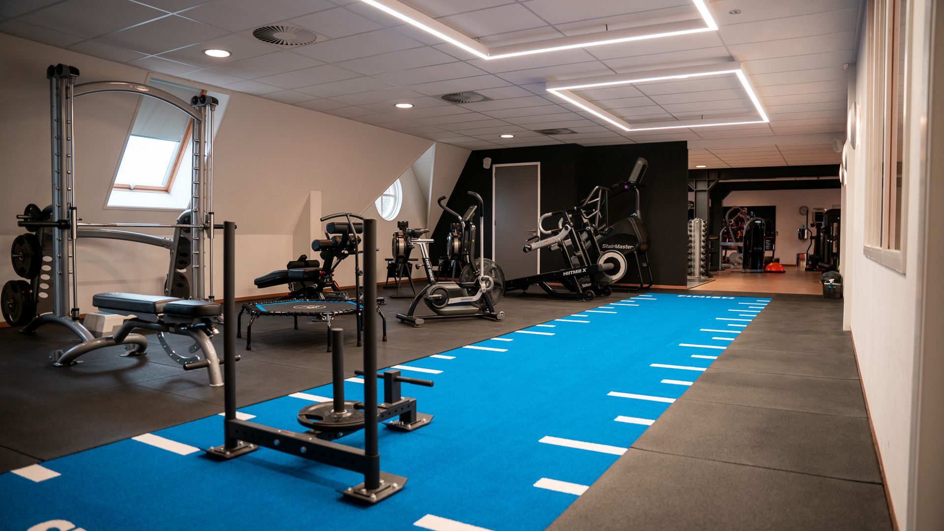Een sportschool met veel fitnessapparatuur op de vloer