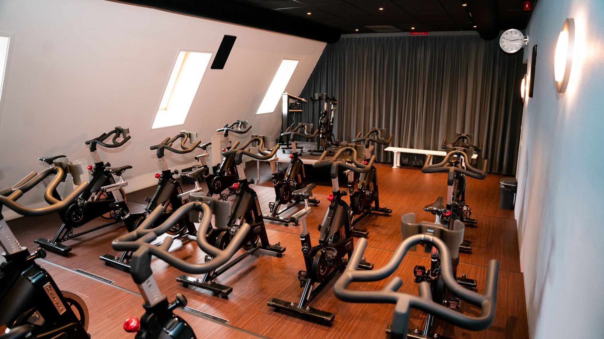 Een sportschool vol met veel hometrainers en spiegels.