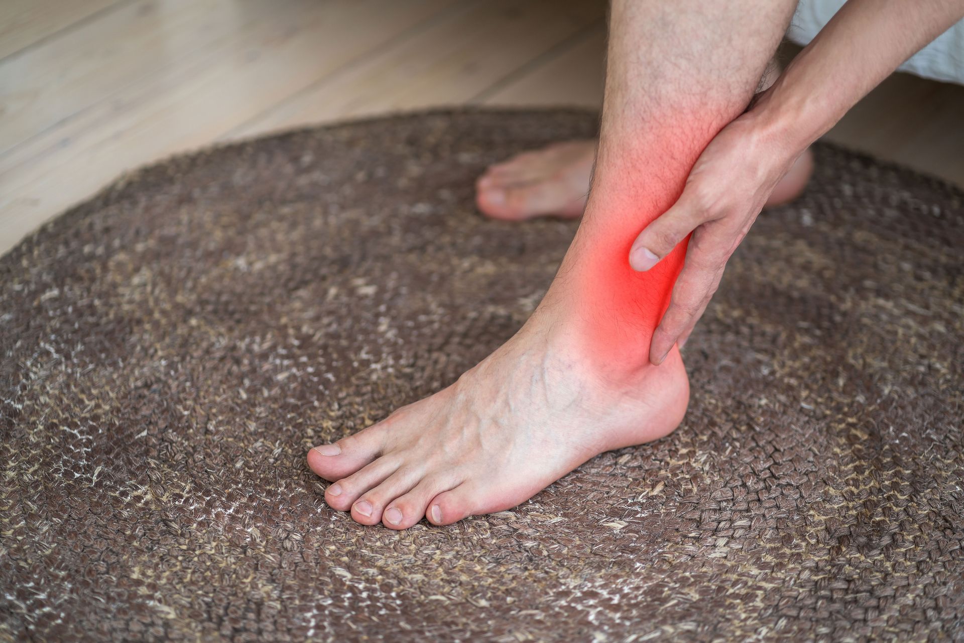 Person holding ankle with red highlight indicating pain.