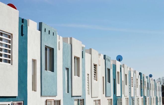 Row of white and teal houses under a clear blue sky.