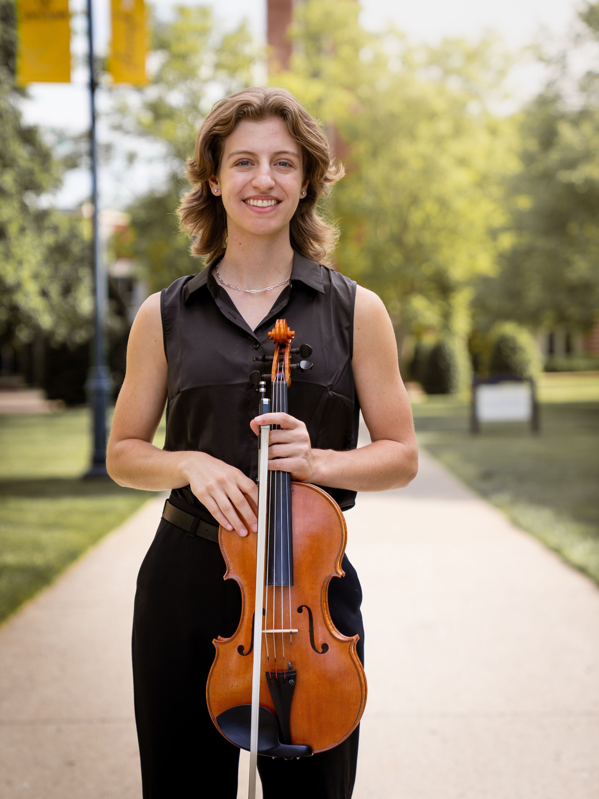 Headshot of Millie Meunier holding her viola and smiling into the camera.