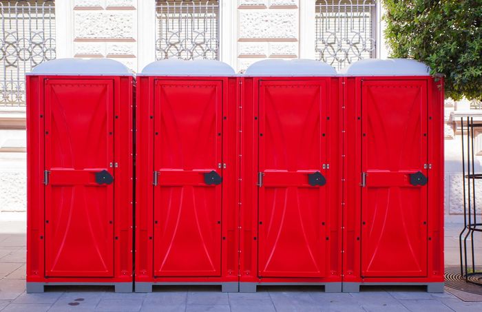 Row of portable toilet rentals arranged outdoors.