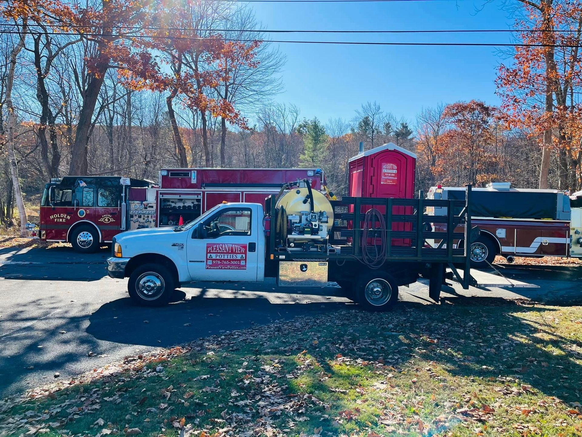 A blue portable toilet is sitting in the middle of a forest.