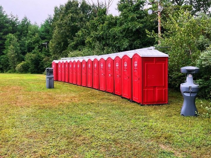 A row of portable toilets in a grassy area.