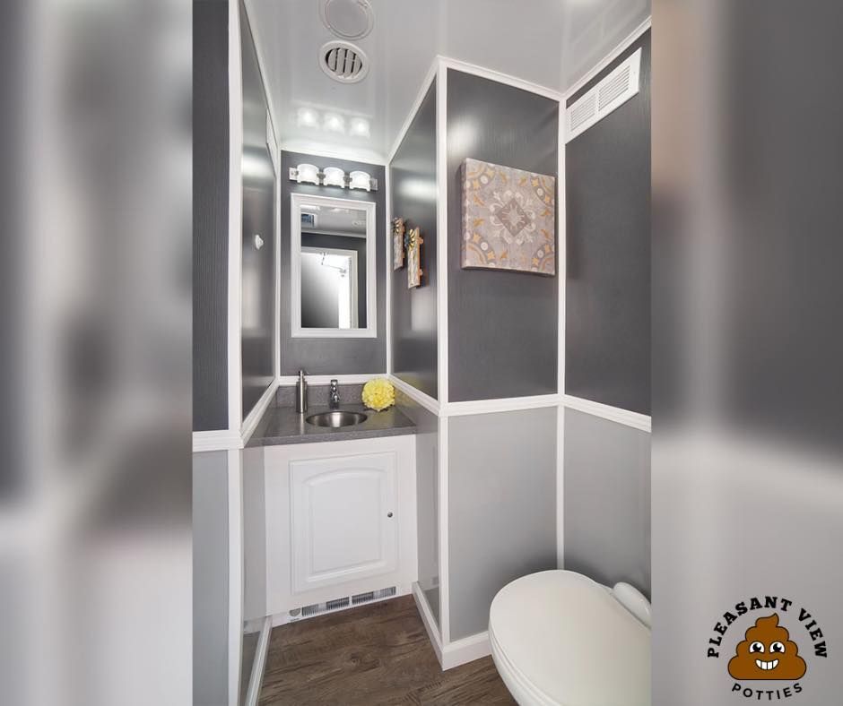 A bathroom with a toilet , sink and mirror.