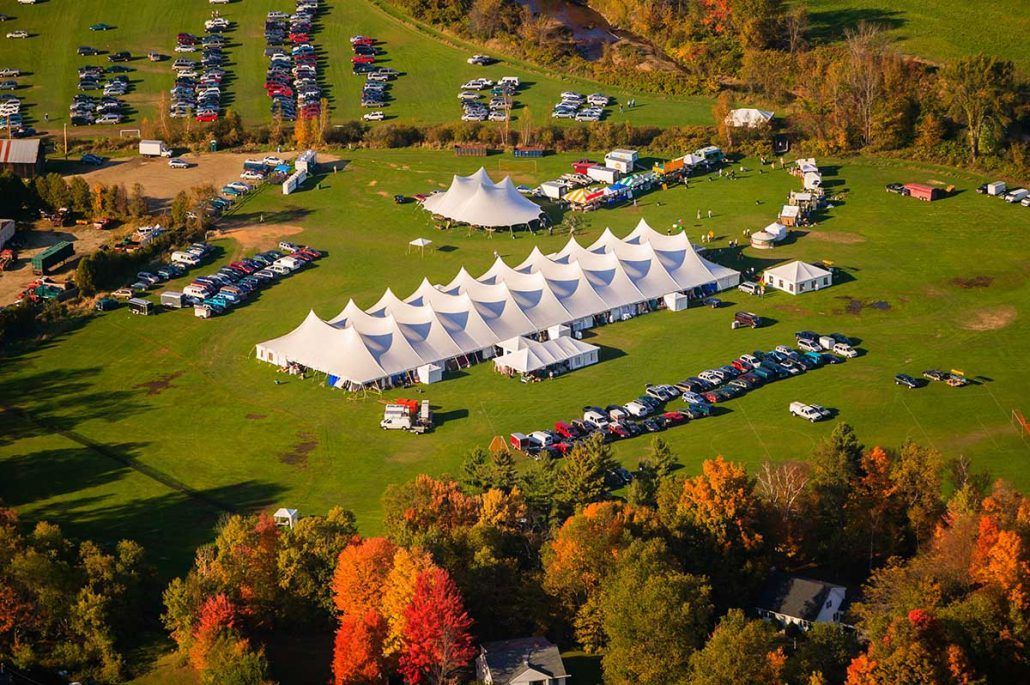 An aerial view of a field filled with tents and cars.