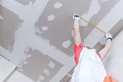 A man is plastering a wall in a room.