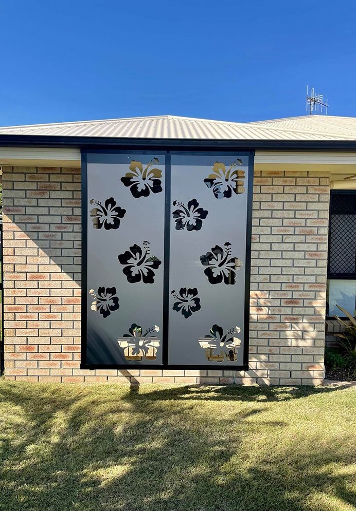 A Brick House With A Sliding Glass Door With Flowers On It — Affordable Screens & Blinds in Thabeban, QLD