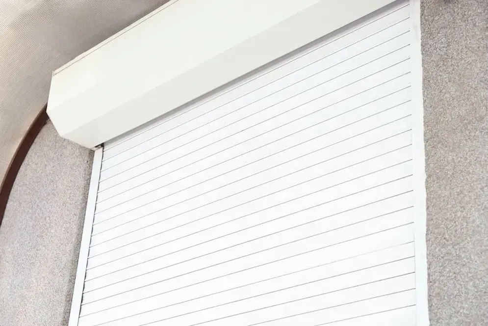A Close Up Of A White Roller Shutter On A Window — Affordable Screens & Blinds in Thabeban, QLD