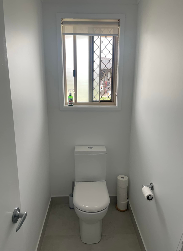 A Toilet Is In A Small Bathroom Next To A Window — Affordable Screens & Blinds in Thabeban, QLD