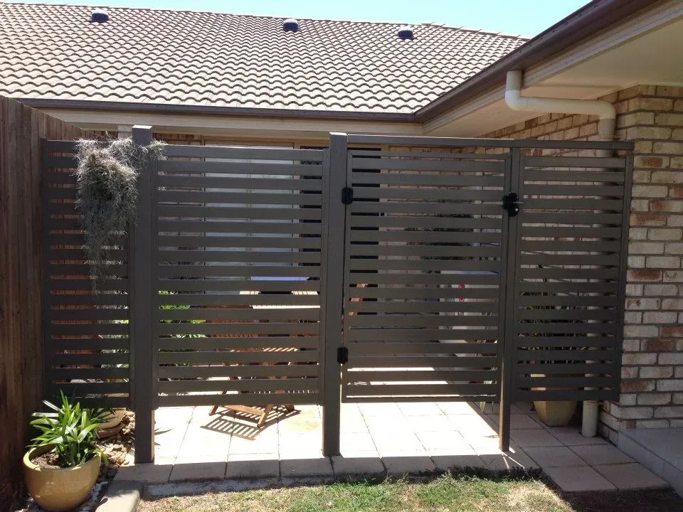 A Fence With A Gate In Front Of A Brick House — Affordable Screens & Blinds in Thabeban, QLD