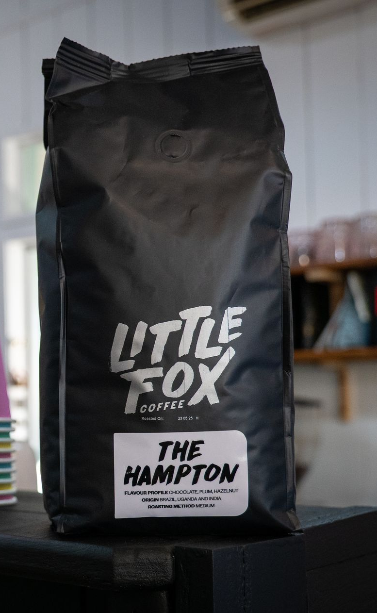 Black coffee bag, "Little Fox Coffee," "The Hampton" label, on a counter.