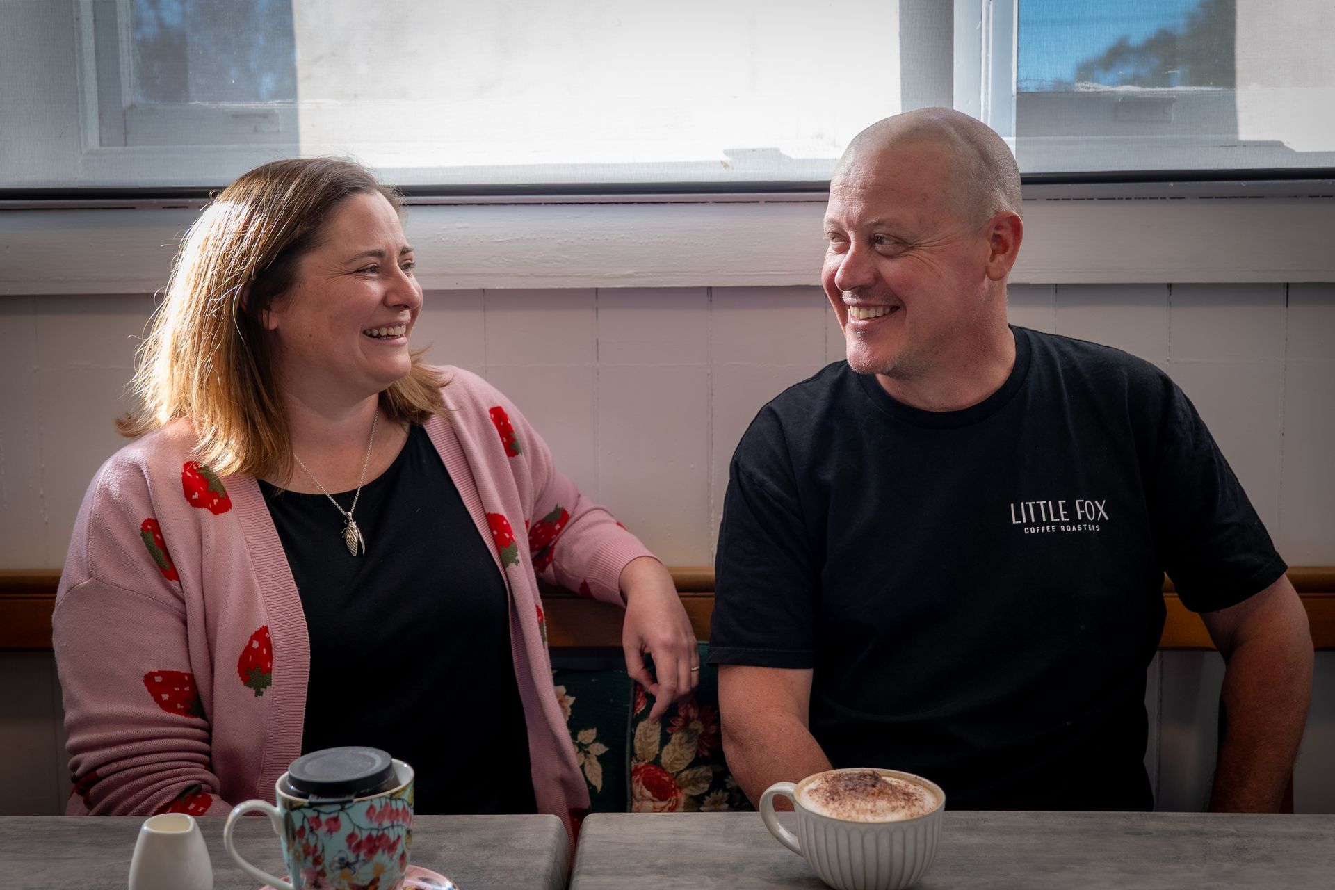 A woman and a man are looking at each other while having a beverage.