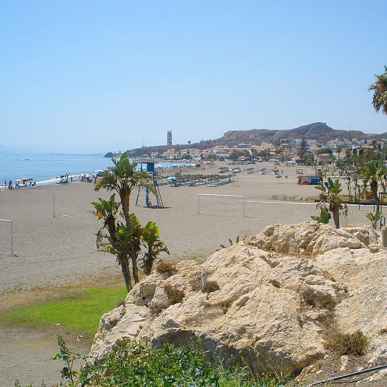 Una playa con una torre de salvavidas en la distancia.
