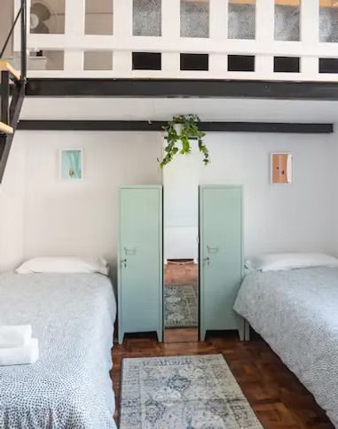 Un dormitorio con dos camas, dos armarios y una escalera.