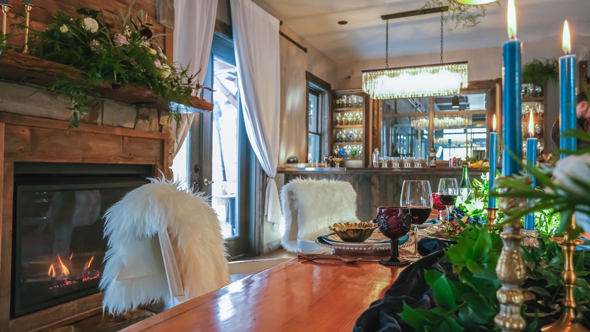 A living room with a table , chairs , candles and a fireplace.