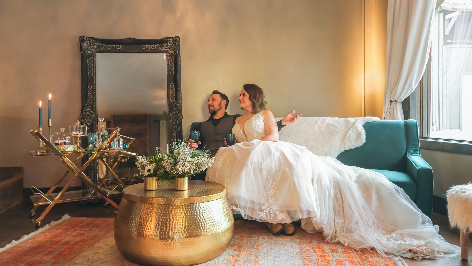 A bride and groom are sitting on a couch in a living room.