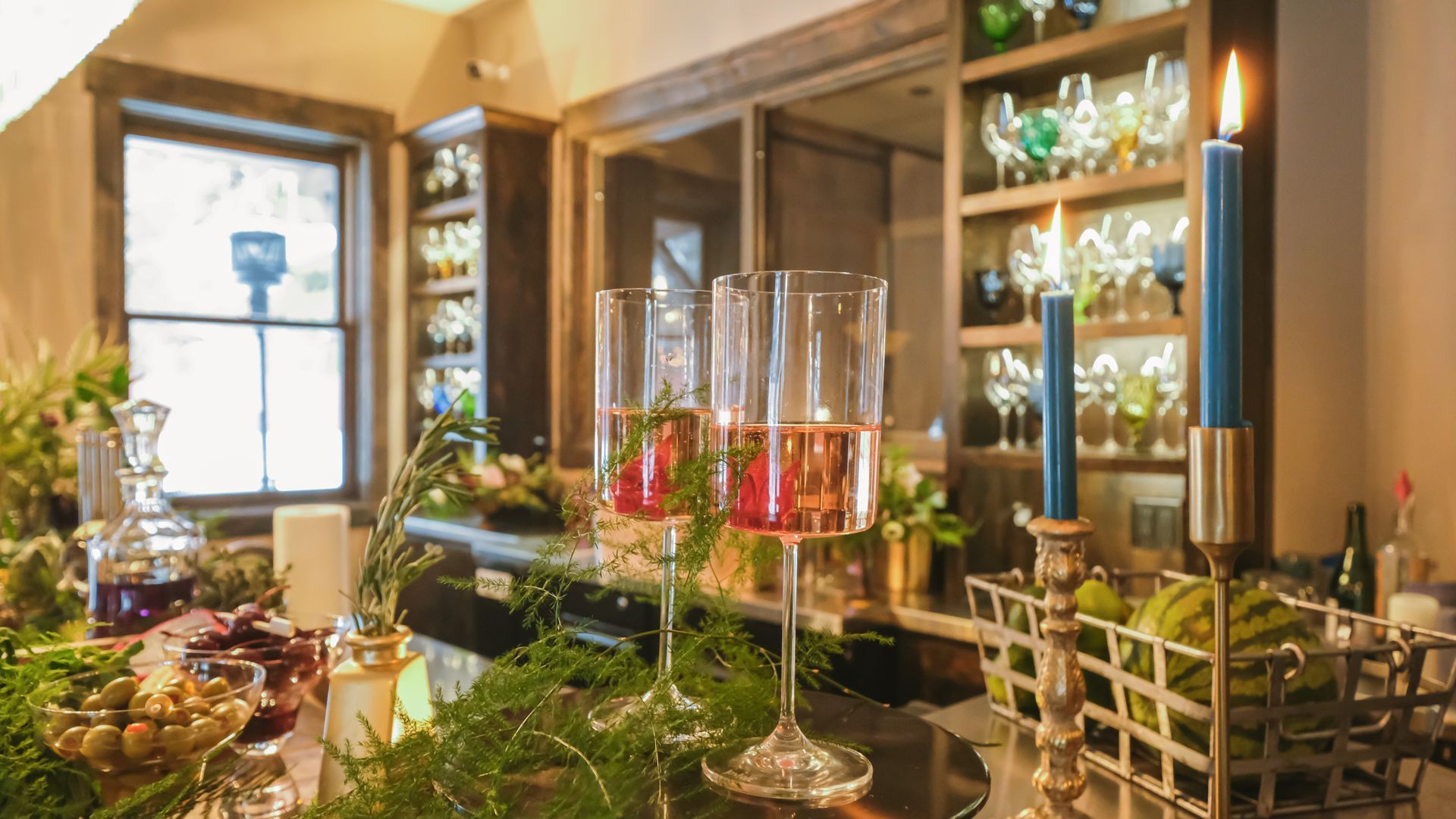A room with a lot of candles and glasses on a table.