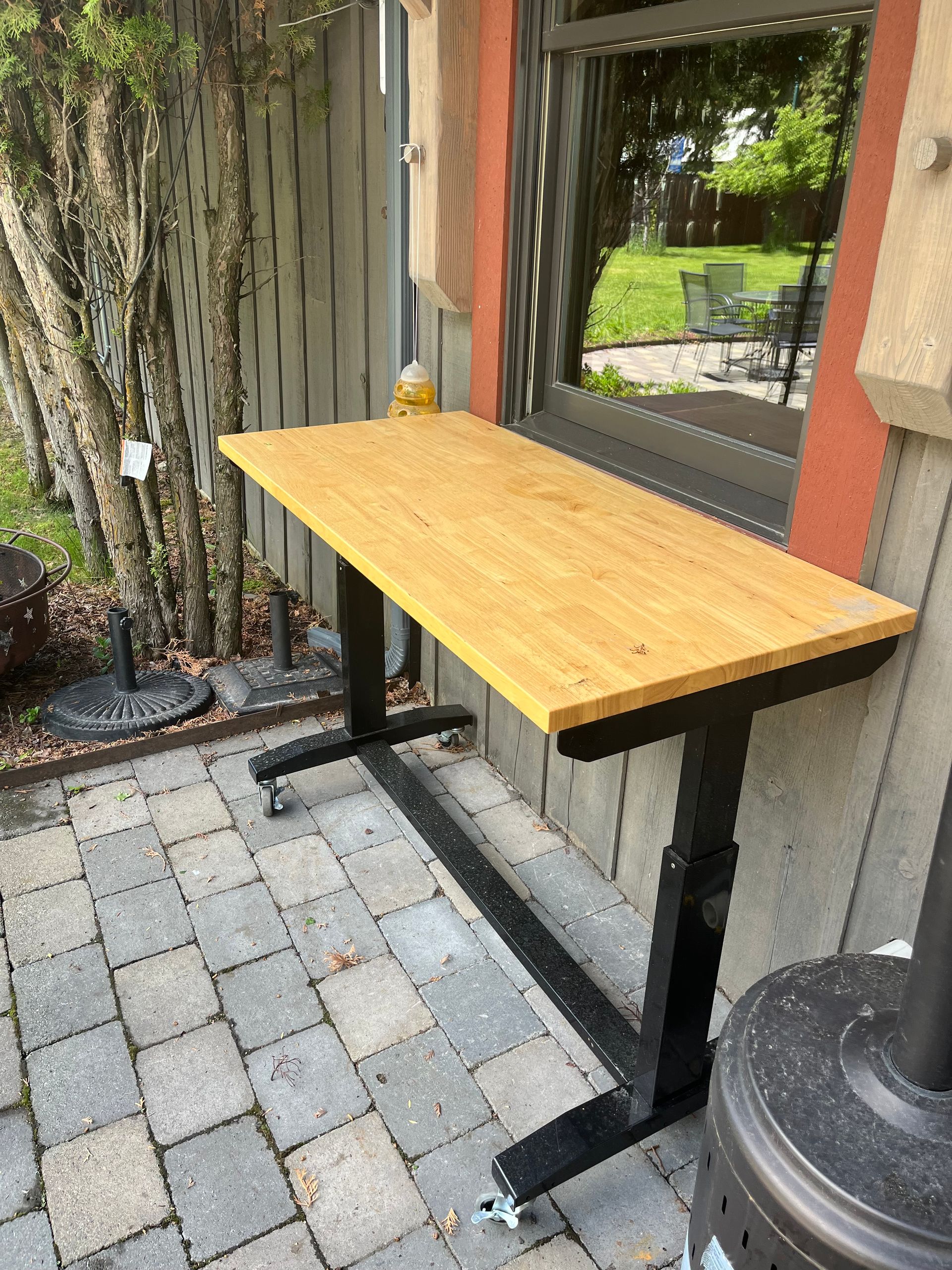 A wooden table is sitting on a patio next to a window.
