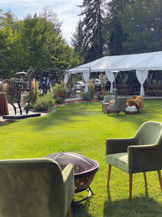 A tent is sitting in the middle of a lush green field with chairs and a fire pit.