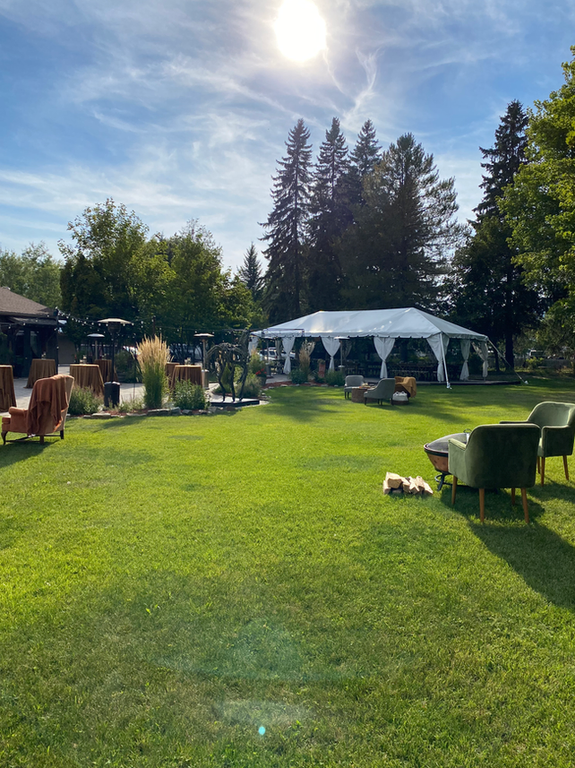 A large grassy field with a tent and chairs in it.