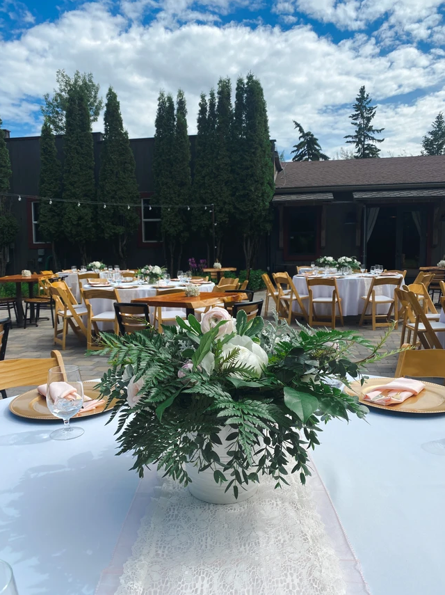 A vase of flowers is on a table at a wedding reception.