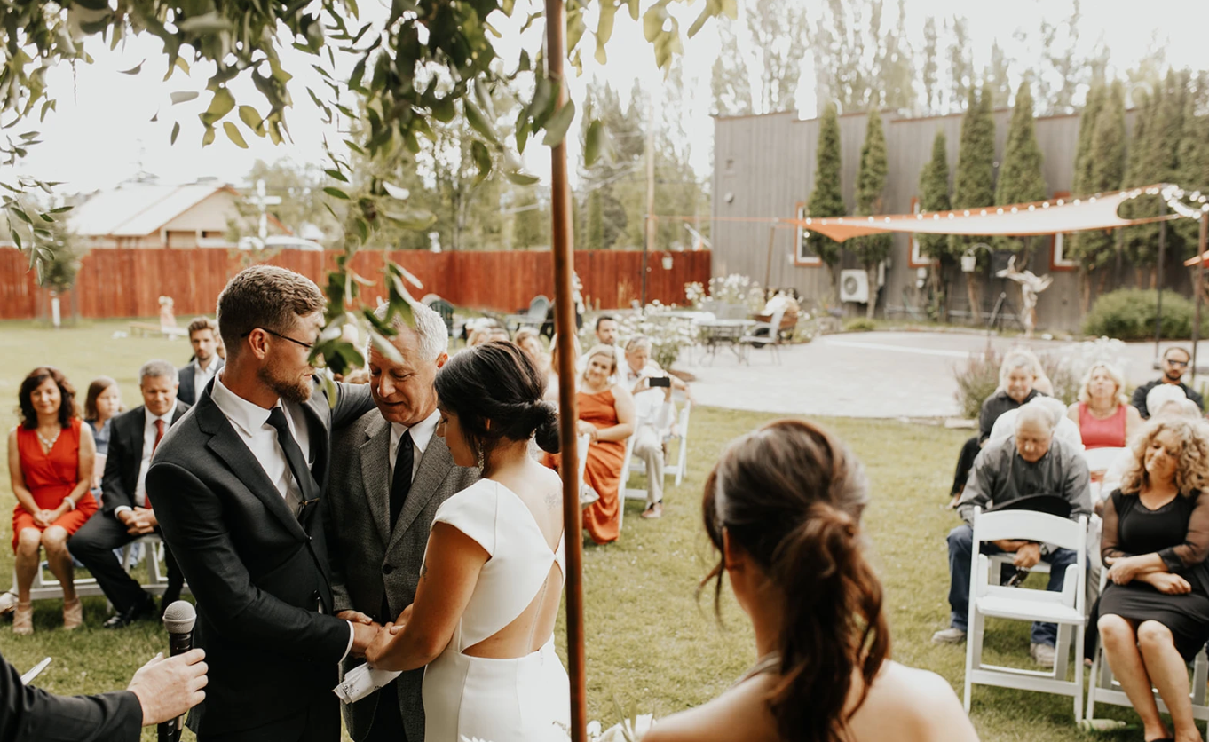 A bride and groom are holding hands during their wedding ceremony.