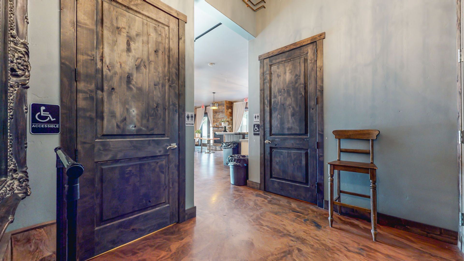 A hallway with a handicap sign on the door and a chair.