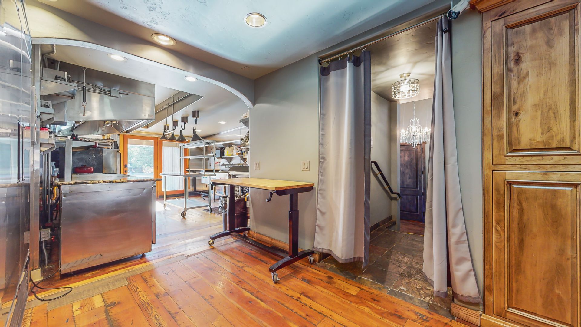 A 3d rendering of a kitchen with wooden floors and stainless steel appliances.