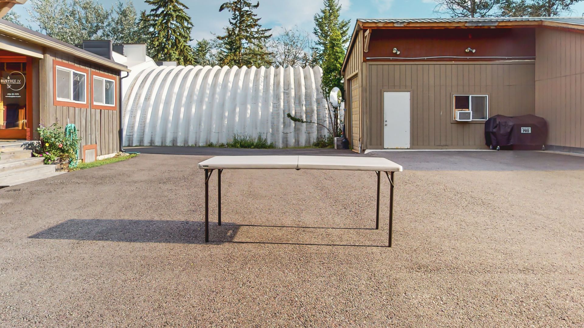 A table is sitting in the middle of a gravel driveway in front of a building.