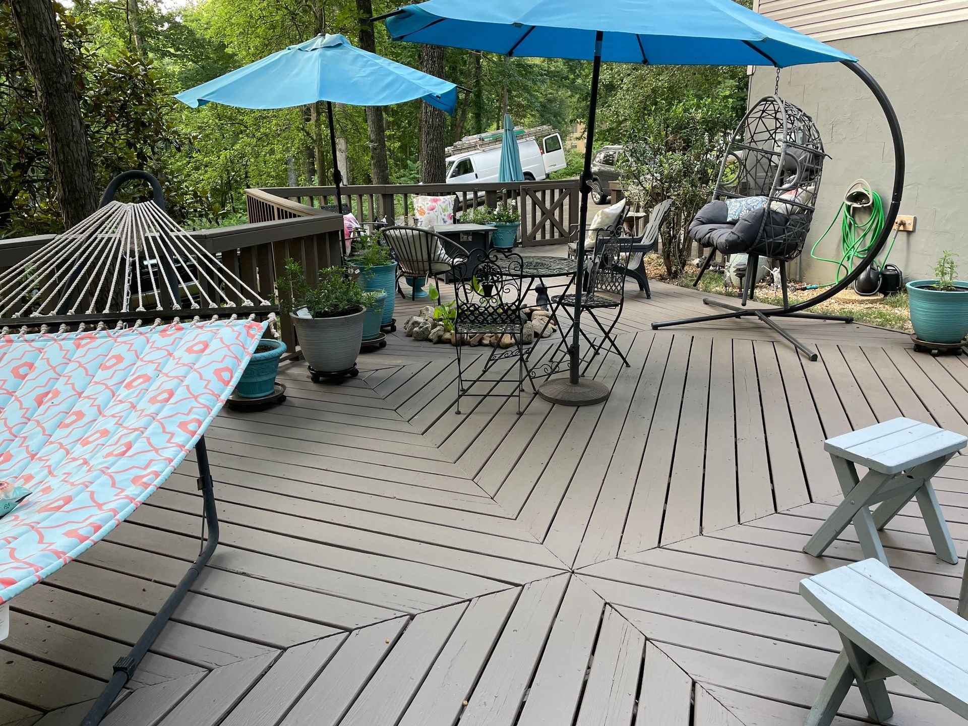 A deck with umbrellas , chairs , a hammock and a swing.