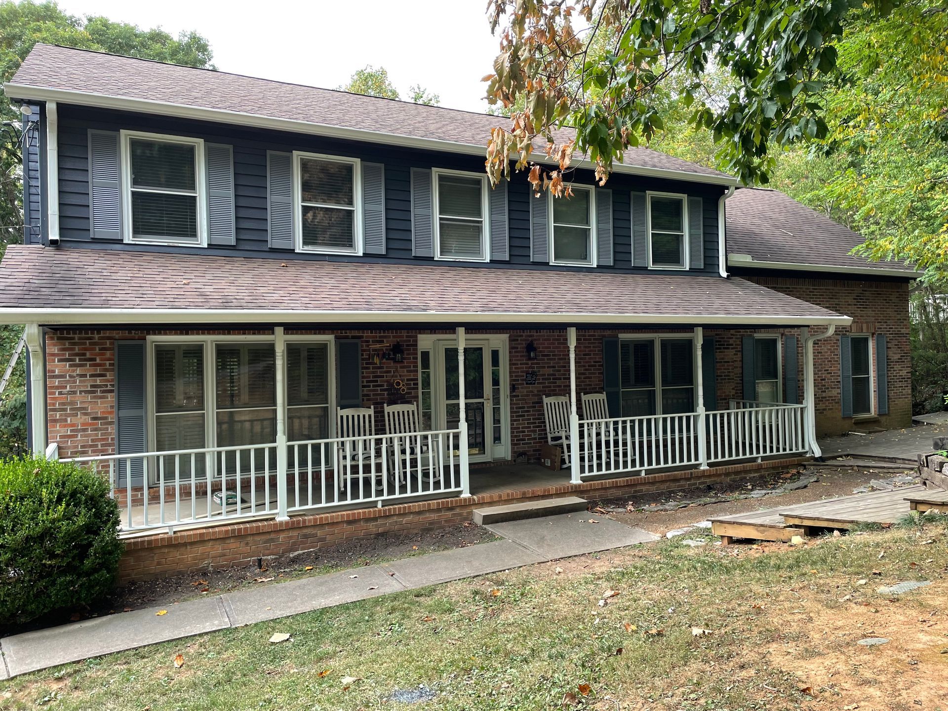 A large brick house with a large porch and shutters.