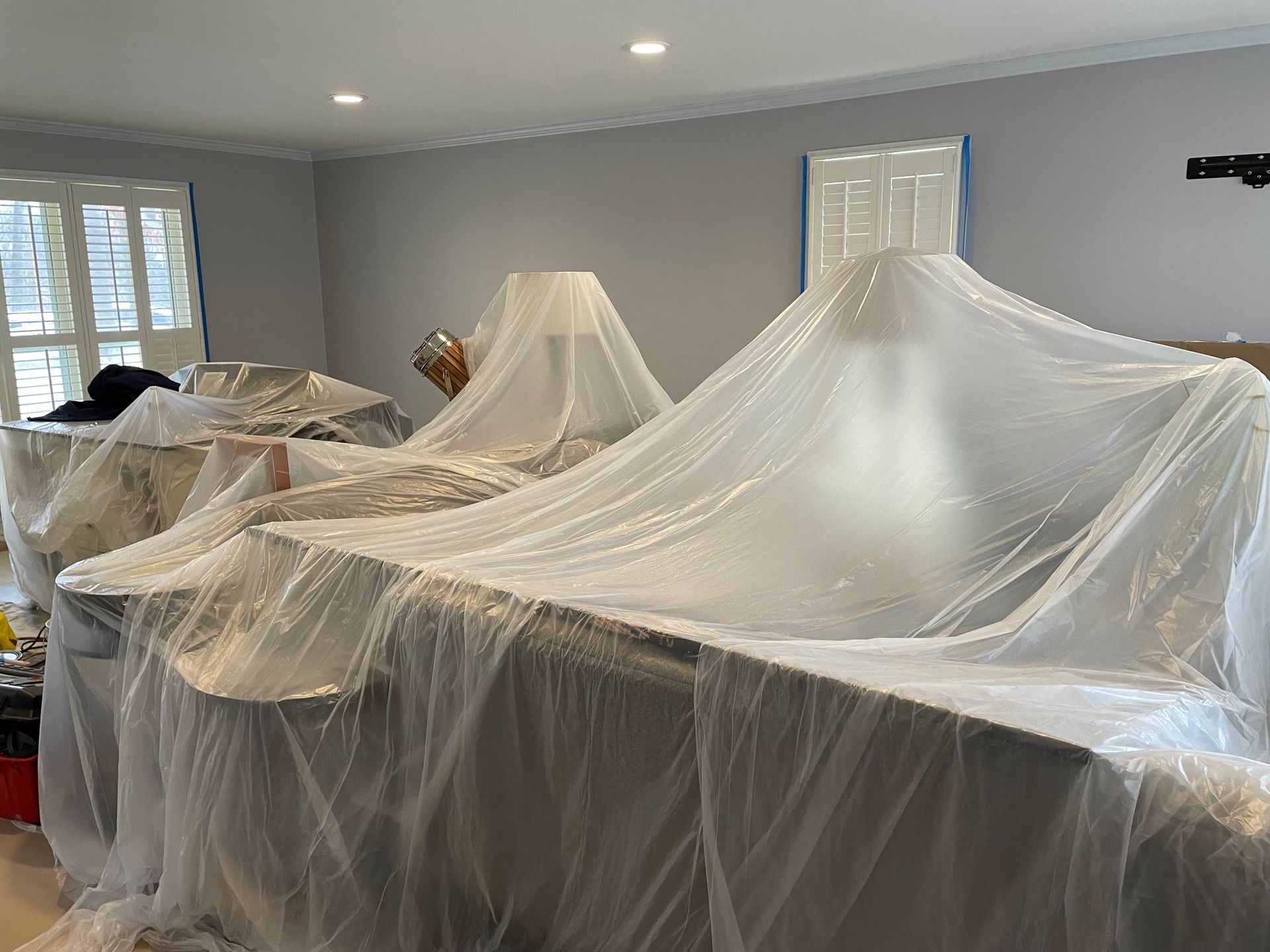 A living room is being painted and covered in plastic.