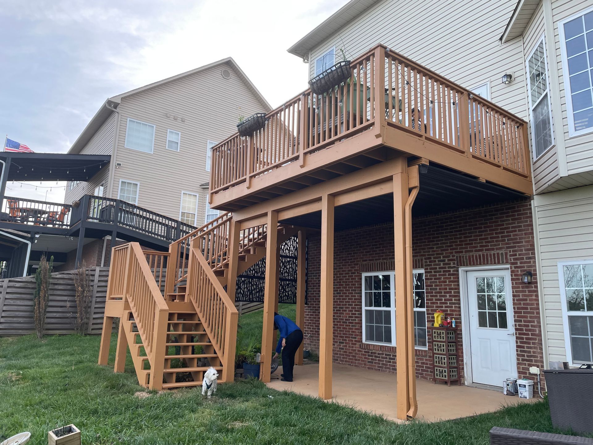 A man is working on a wooden deck in the backyard of a house.