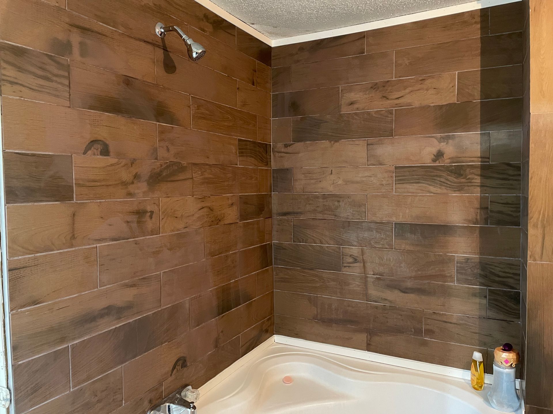 A bathroom with a tub and a shower with wooden tiles on the walls.
