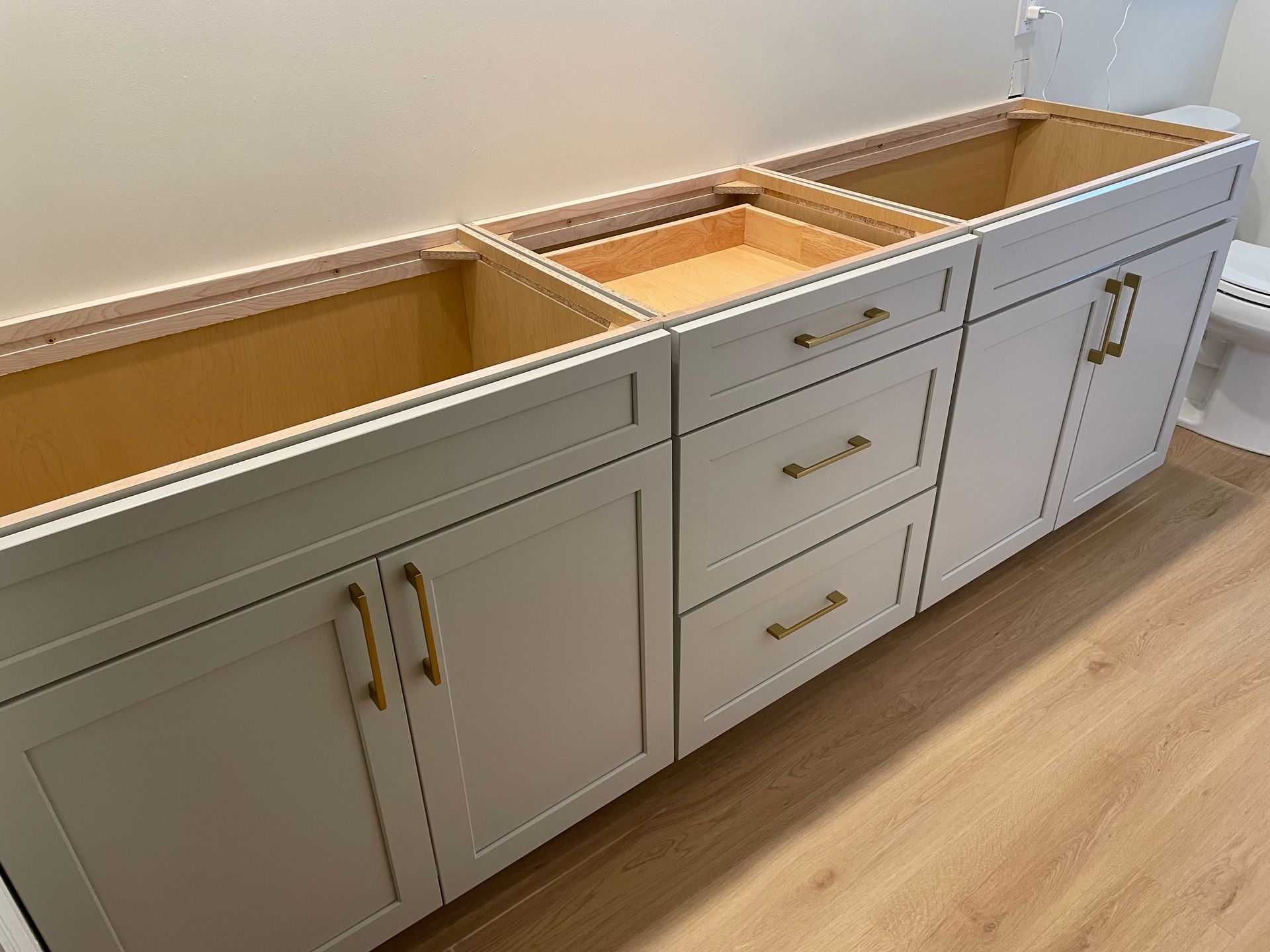 A bathroom vanity with white cabinets and drawers is being built.