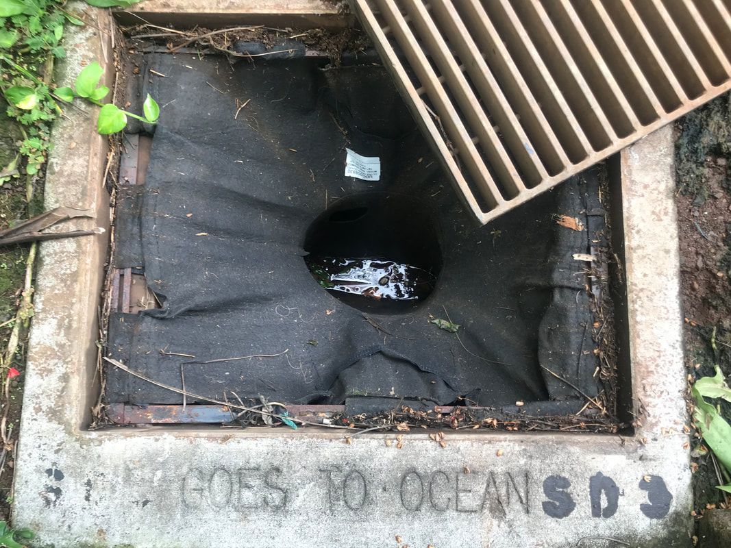 Open storm drain with a black fabric insert and an embossed message: 
