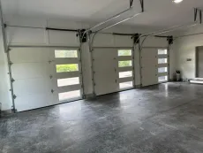 A garage with three white garage doors and a concrete floor.