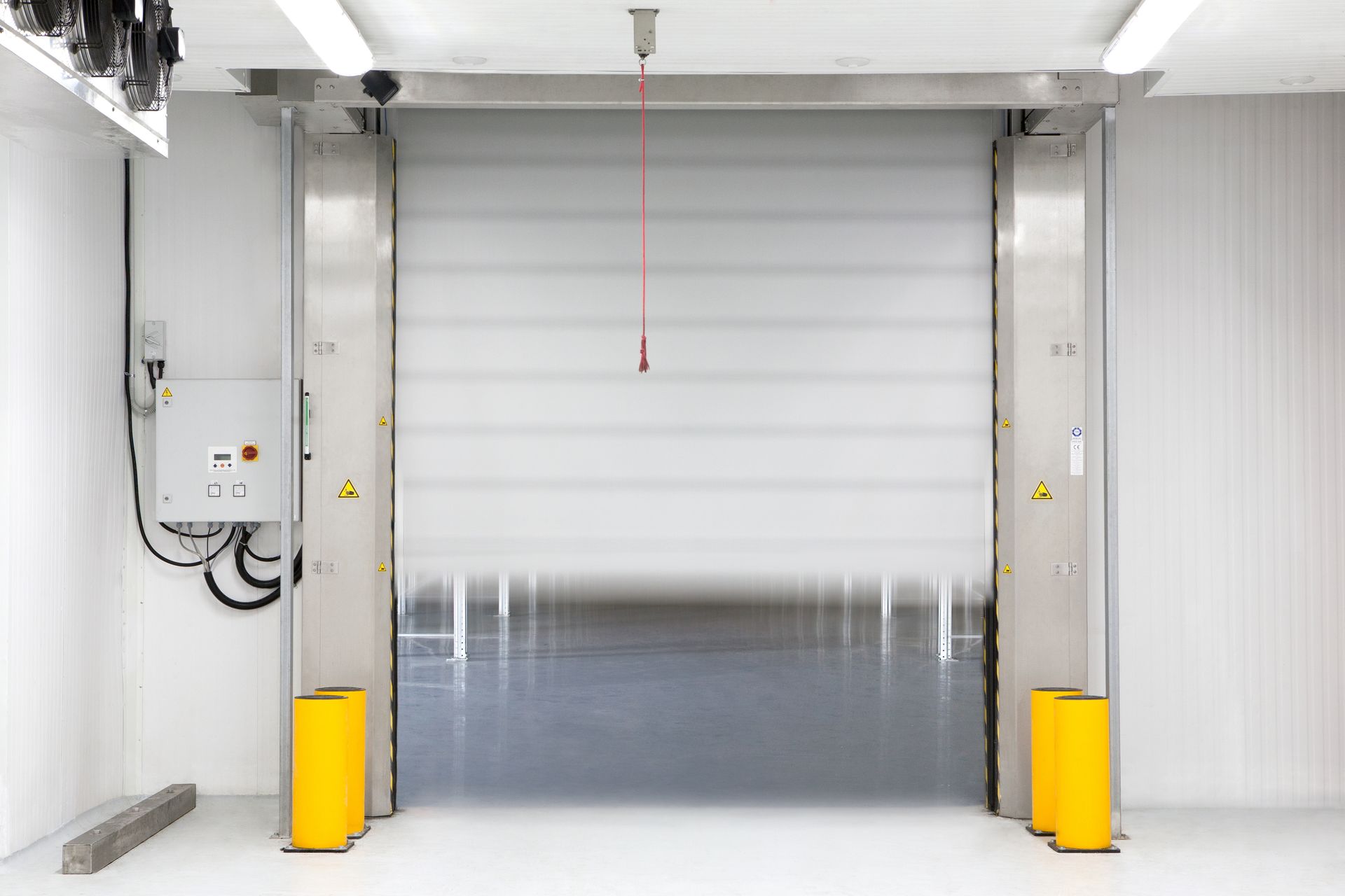 A stainless steel roller door is open in a warehouse.