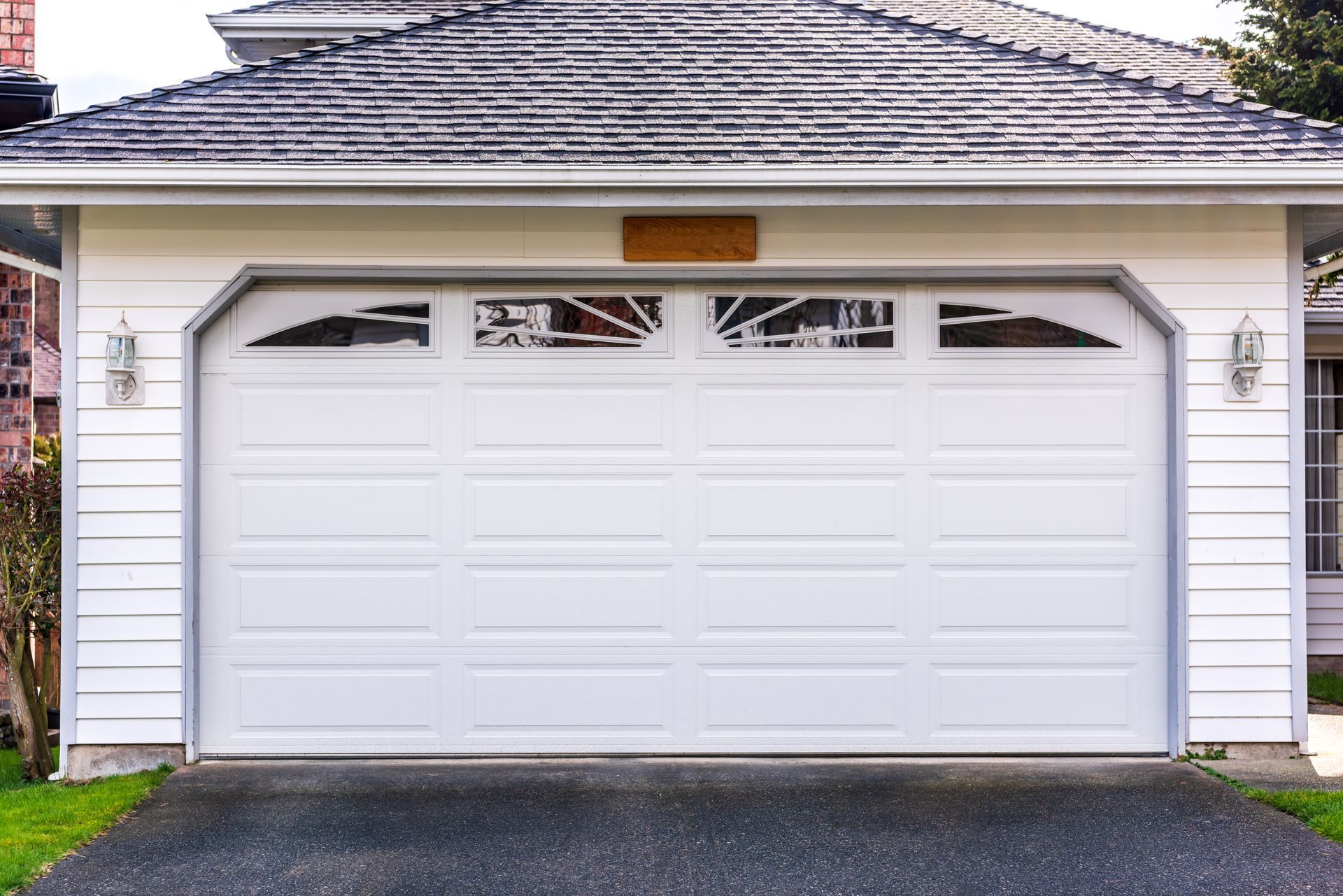 A white garage door is open in front of a house.