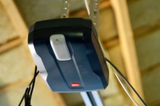 A garage door opener is hanging from the ceiling of a garage.