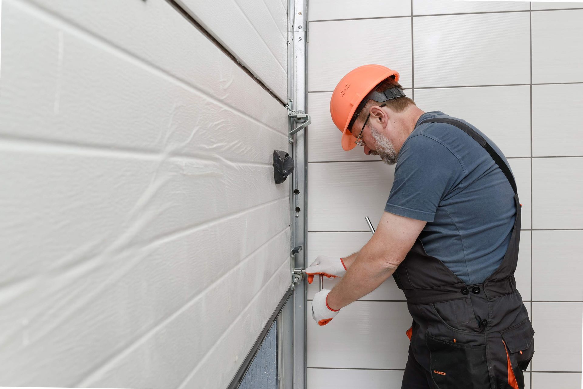 Worker in hard hat fixing a garage door mechanism.