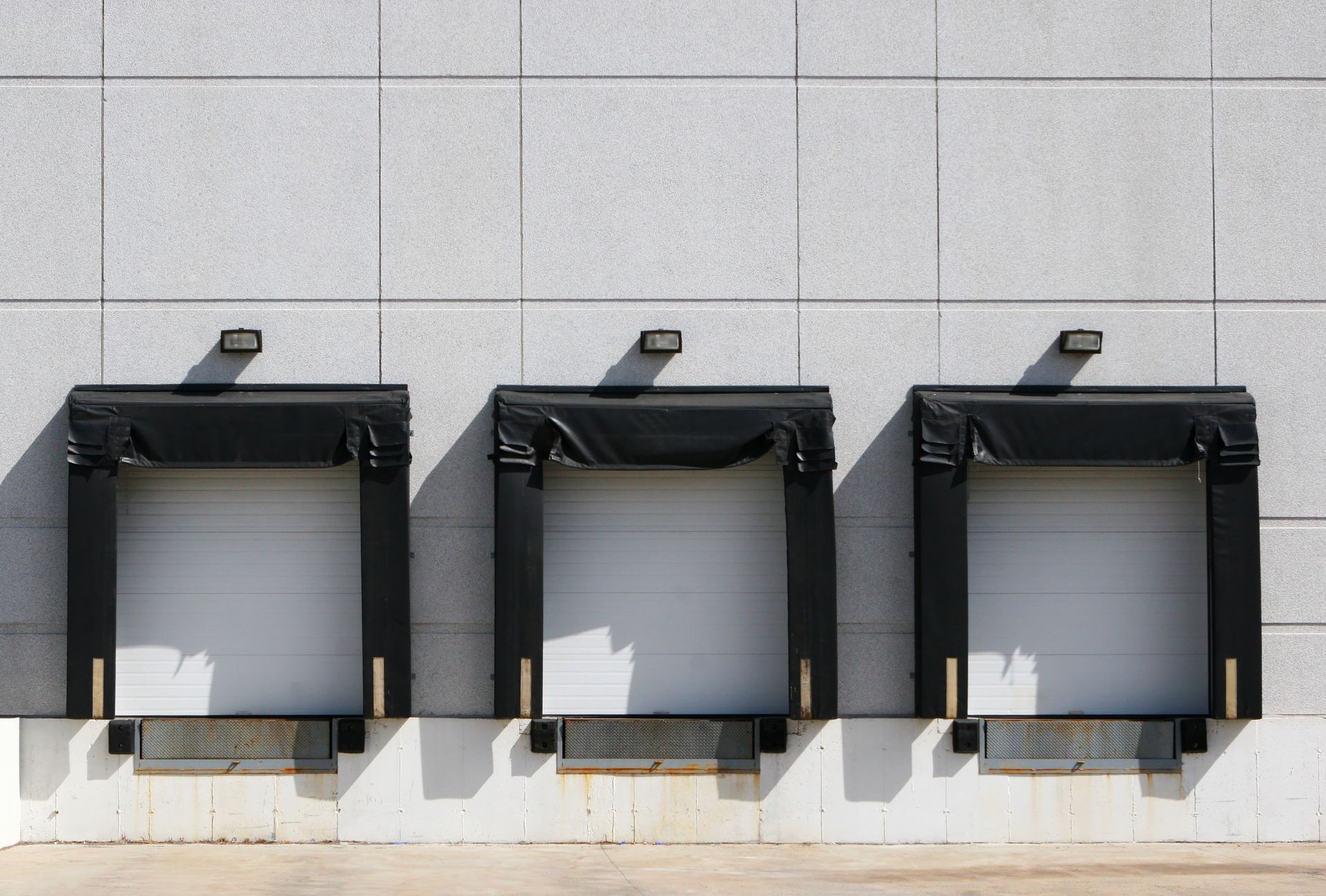 Three empty loading dock doors on a gray building exterior.